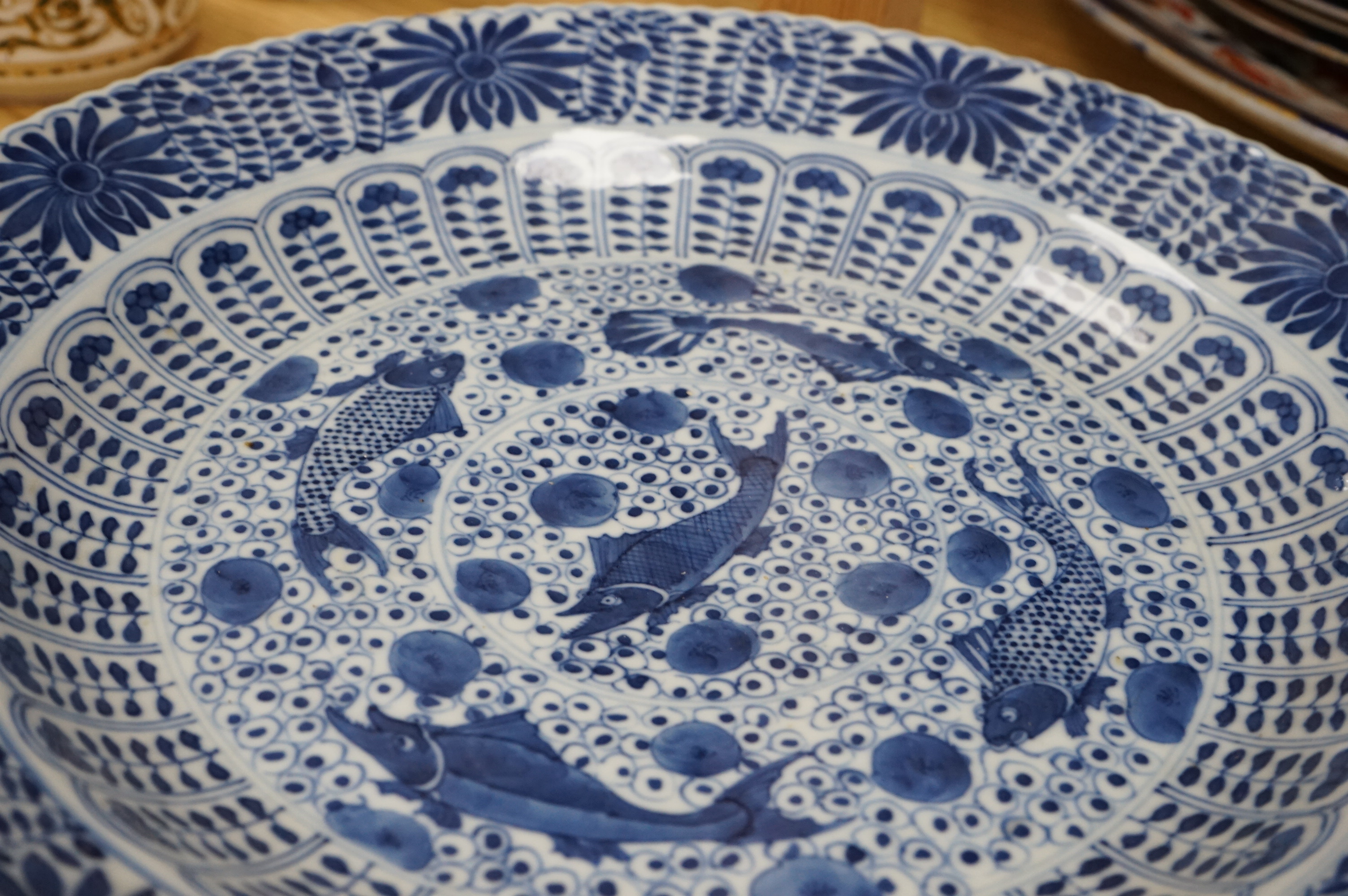 A Chinese blue and white 'fish' dish, Kangxi mark but c.1900, 33cm diameter. Condition - slight chipping to rim